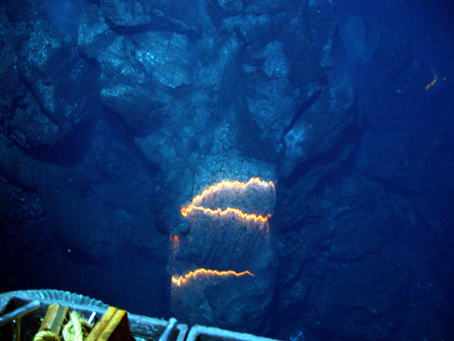 Bands of glowing magma, about 2,200 degrees Fahrenheit, are exposed asa pillow lava tube extrudes down slope