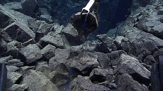 Deep Discoverer's robotic arm sampling an angular cobble of basalt