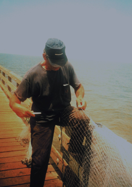 A mullet fisherman mending his net on the Gandy Bridge catwalk