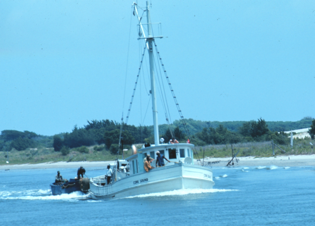 A small menhaden vessel with auxiliary boats being towed astern