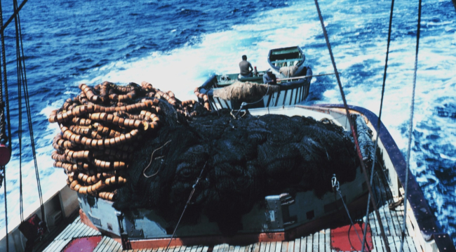 Nets, purse seine boat, and wake are seen as looking aft from the stern of a tuna boat in the tropical Pacific