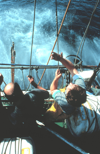 One fisherman holds the pole from the deck while another, higher up, pulls theattached cord when the tuna takes the bait
