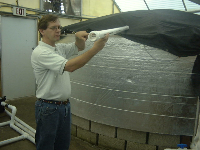 Harbor Branch staff showing pipe system used for recirculating tanks