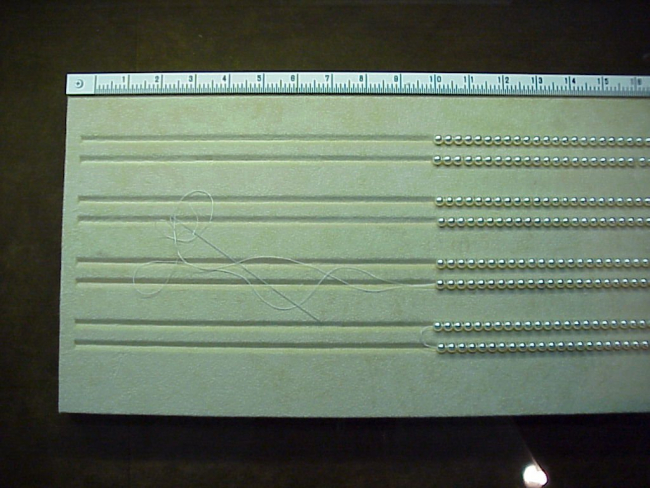 The slotted board used for stringing cultured pearls and measuring the lengthof the necklace or bracelet