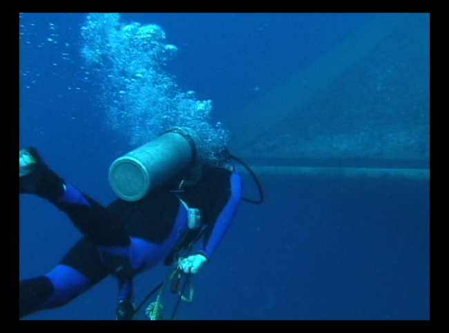 A diver swimming toward the offshore cage in Hawaii with equipment