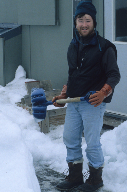A seal researcher doing double duty shoveling snow at an AMLR field station