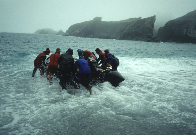 A team of AMLR scientists pushes their Zodiac off the beach at Seal Island toan area deep enough to lower the outboard motor