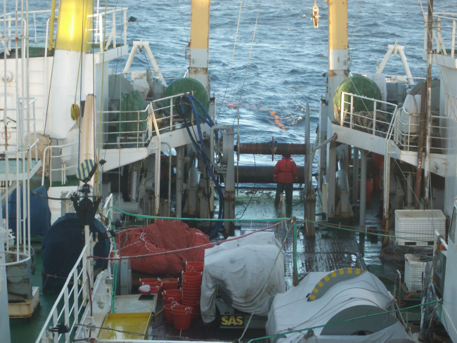A Russian crew member watches the fish net as it is deployed off the stern ofthe ship