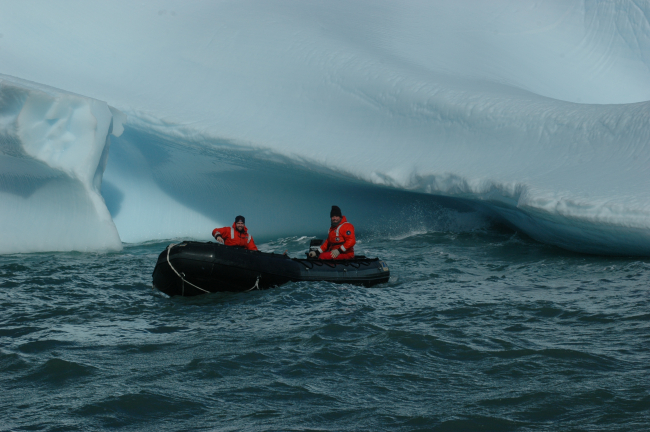 AMLR scientists Ryan Driscoll and Adam Jenkins in a Zodiac, next to an iceberg