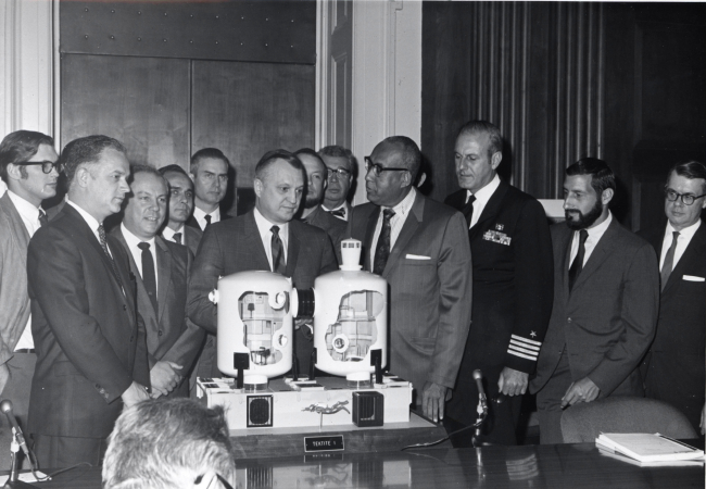 Wally Hickel, Secretary of the Interior, with other dignitaries and Tektiteaquanauts inspecting a model of the Tektite II manned undersea habitat