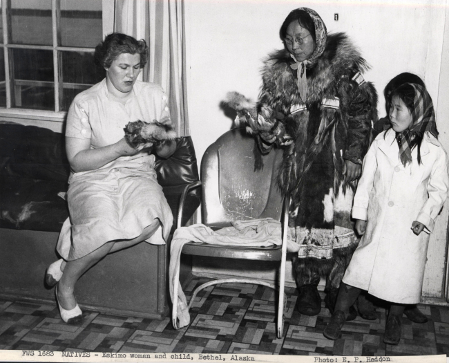 Eskimo woman and children selling fur dolls