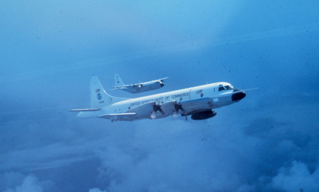 NOAA P-3 N42RF in flight; NOAA C-130 N6541C flying outboard of P-3