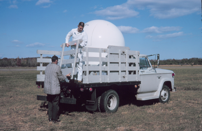 Station Number 002 - occupied successively in 1964 and 1965Party Chiefs,  Charles Burroughs, Sherrill Snellgrove, and Bob StevensLieutenant Dee Kimball, ESSA Corps, in truck and Charles Clarke loading acamera dome for shipment