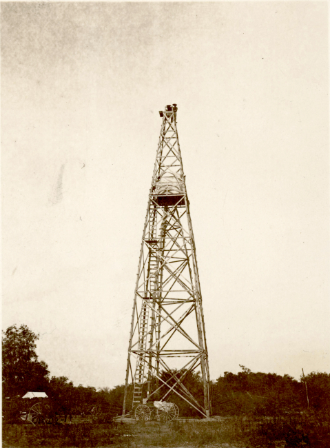 A large wooden tower with wagon below and man at top for scale