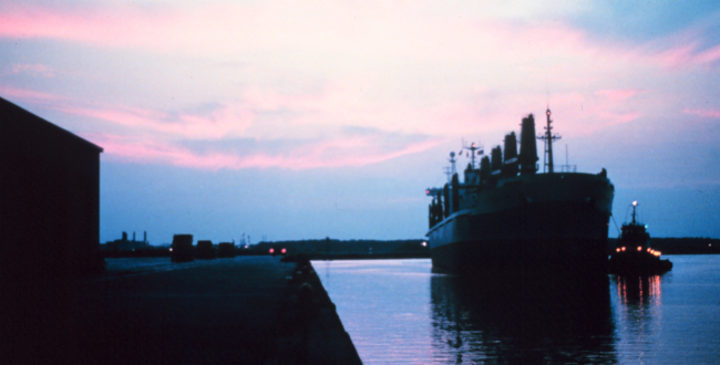 A large break-bulk merchant vessel docking at sunset at Lake Charles
