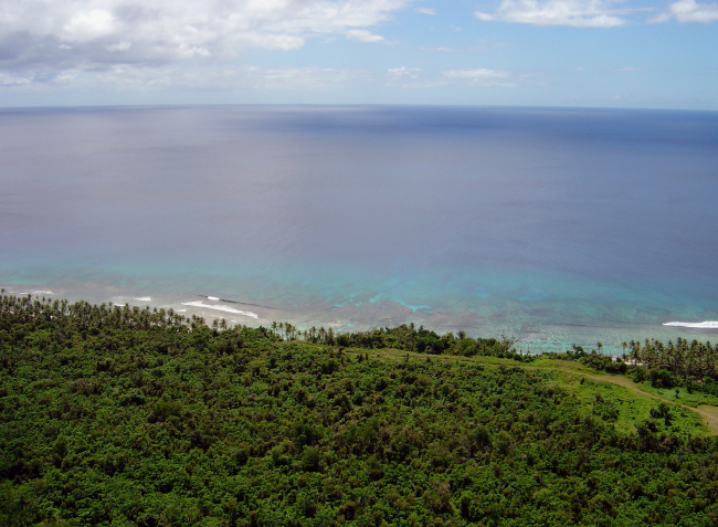 Looking down over the Guam jungle to the reef and surf far below