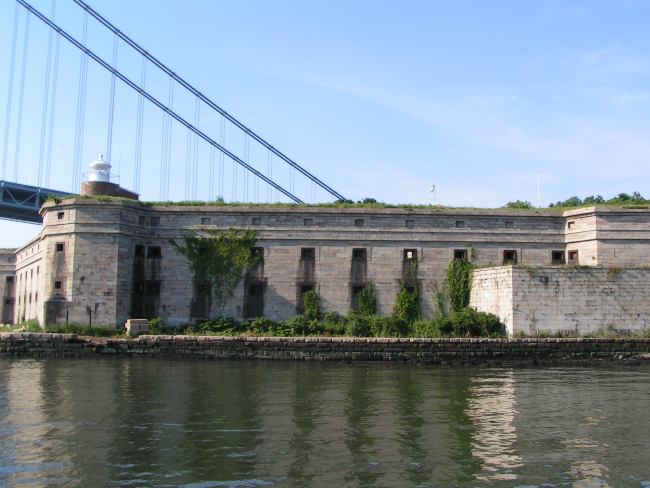 Fort Wadsworth and the Fort Wadsworth Lighthouse on the upper left of thefort with the western terminus of the Verrazano-Narrows Bridge in the background