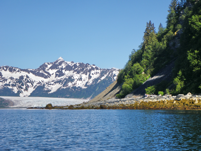 Rocky shoreline, a glacier coming to the sea, and high mountain peaks