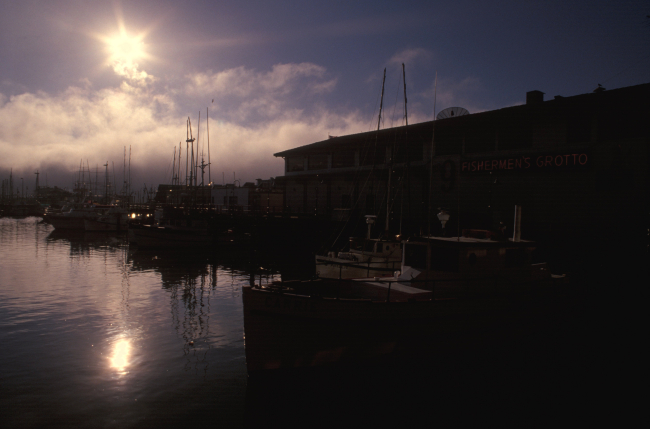 The Monterey waterfront silhouetted in the late afternoon with fog billowing inoff the sea