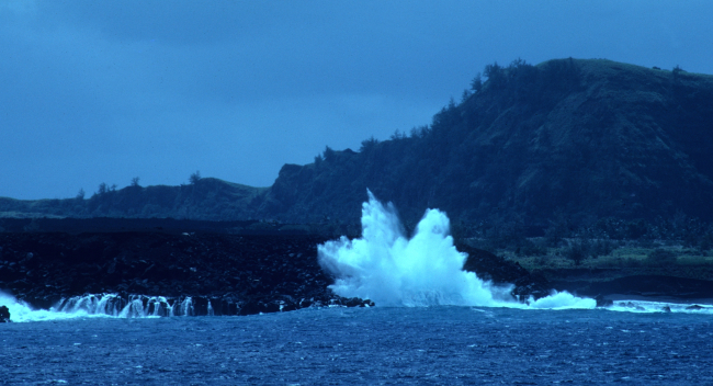 Surf crashing on the volcanic shores of Pagan Island
