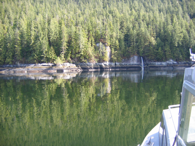 Horizontal strata on the shoreline and reflections in the still waters ofErnest Sound