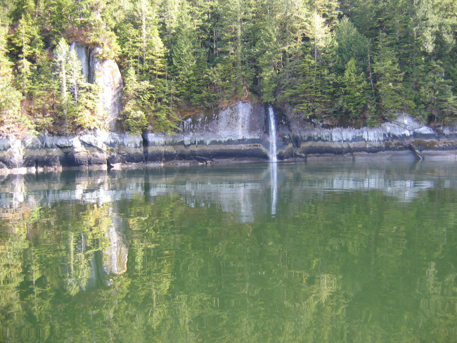 Horizontal strata on the shoreline and reflections in the still waters ofErnest Sound