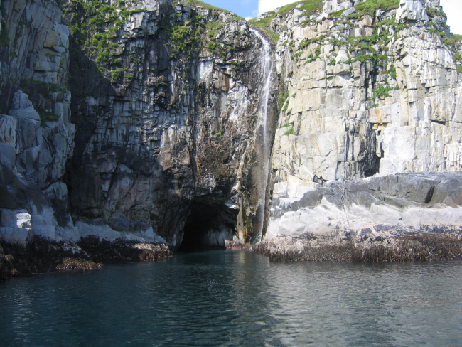 A cheerful little waterful entering the sea near a sea cave on Little KoniujiIsland