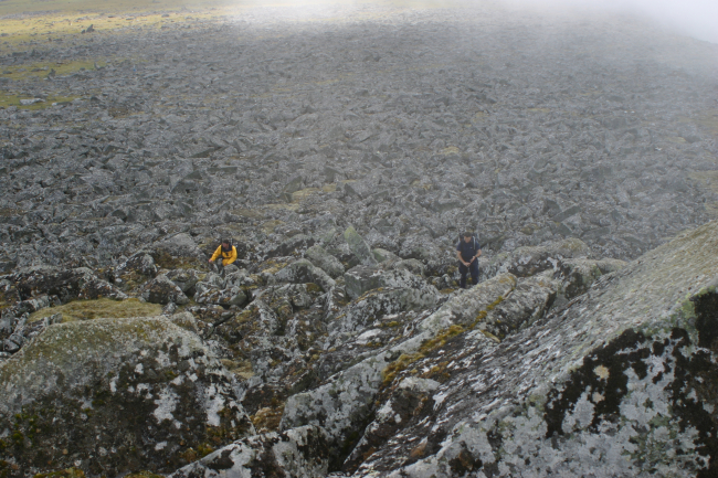 Hiking through lichen covered boulders on the flat summit of Little DiomedeIsland