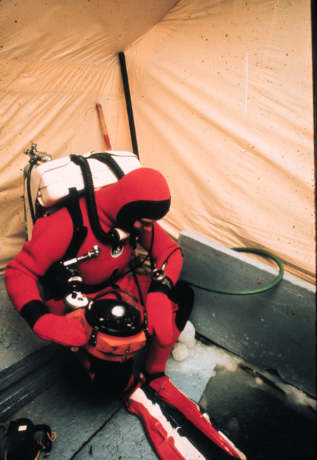 Diver with rebreather and heated dry suit prepares to descend into the ice