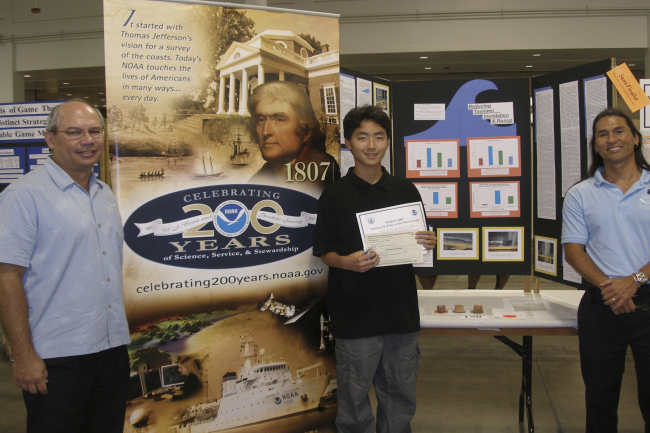 Bill Thomas (L) , Director Pacific Services Center, and Manning Taite (R),Environmental Literacy Coordinator, (PSC) are shown at the 50th Hawai'i StateScience and Engineering Fair with the winner of NOAA's Taking the Pulse of thePlanet Award, Christopher Hakoda, a 9th Grade student at Mililani High Schoolon O'ahu