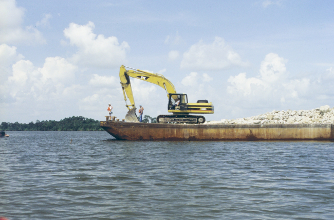 Barge and crane preparing to unload rock