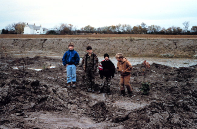 Local children stand in the low marsh area adjacent to the pre-restoredditch of a headwater stream