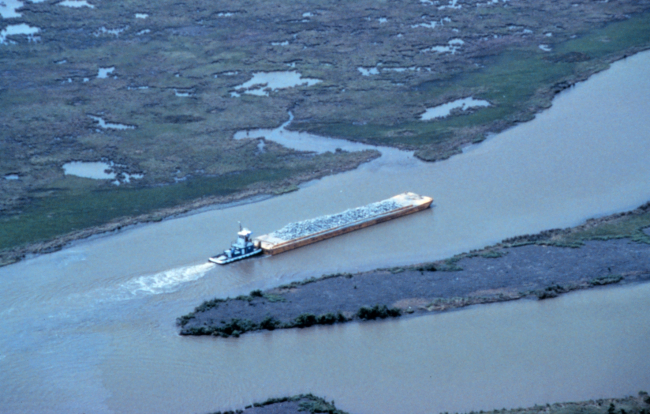 An aerial view of the tug pushing a barge load of rock up Locust Bayou