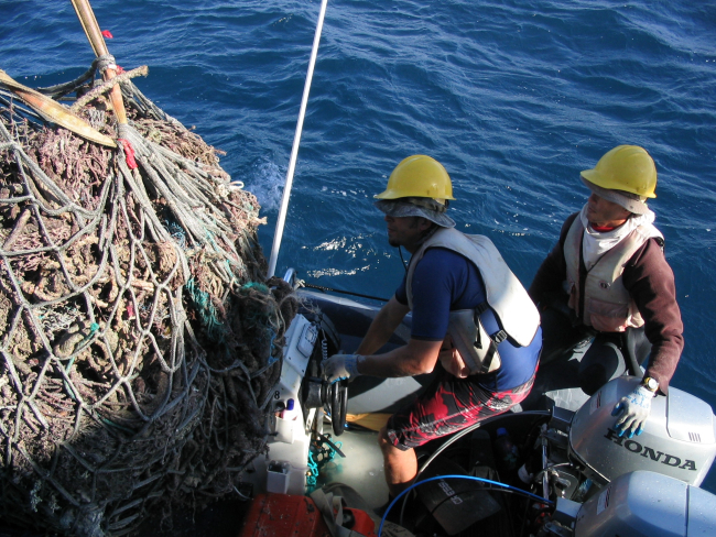 Derelict net debris being removed from inflatable boat and onto deck of CASITAS