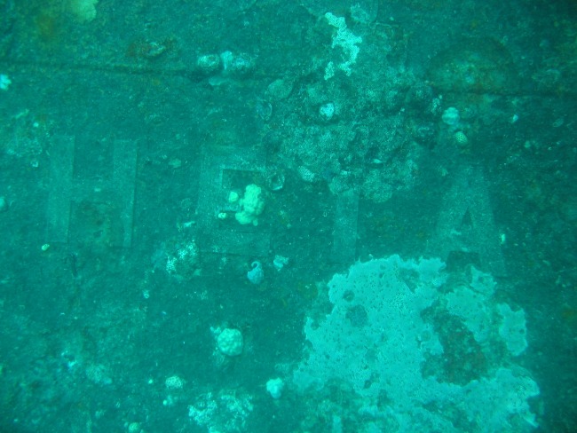 A portion of the Roman letters on the bow of the Heian Maru, a passenger vesselconverted to a submarine tender