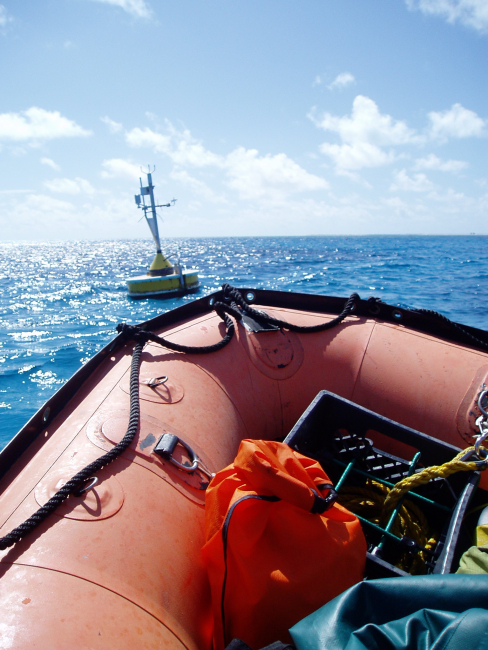 Bow of small boat approaching meteorological buoy to conductmaintenance