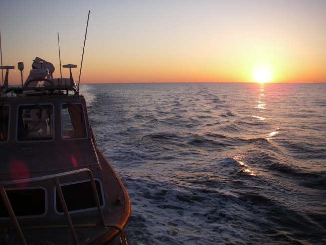 Looking astern at sunset from NOAA Ship THOMAS JEFFERSONover survey launch in davits