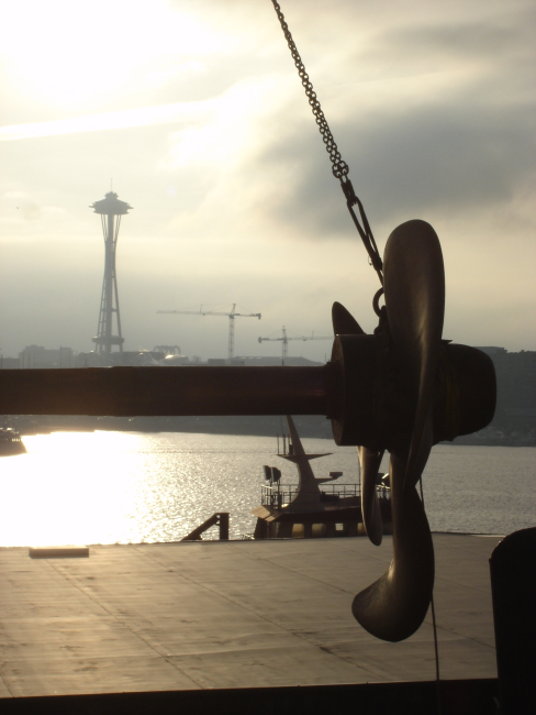 Propeller and shaft of NOAA Ship MILLER FREEMAN being worked onat Seattle shipyard with Space Needle in the background