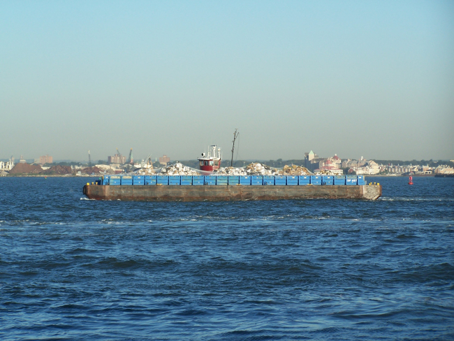 Tug towing garbage barge alongside