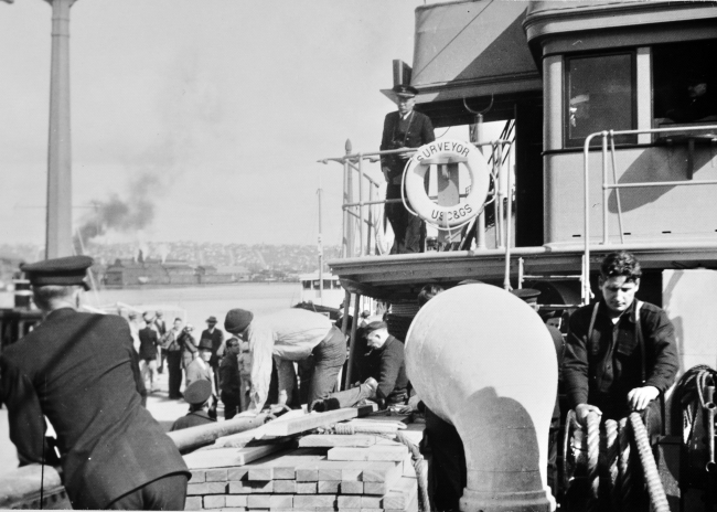 Commanding officer Captain Ray Schoppe on the bridge wing of theSURVEYOR while it docks at the launching of the Coast and Geodetic SurveyShip EXPLORER
