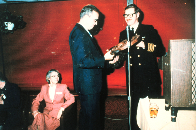 Caaptain Sig Peterson presenting Rear Admiral Harley Nygren with a carvedNOAA Corps insignia upon the occasion of Admiral Nygren's retirement