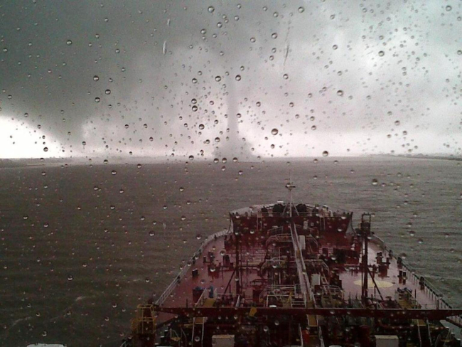 Tornadic waterspout crossing Mississippi River in front of large moving ship onthe Mississippi River