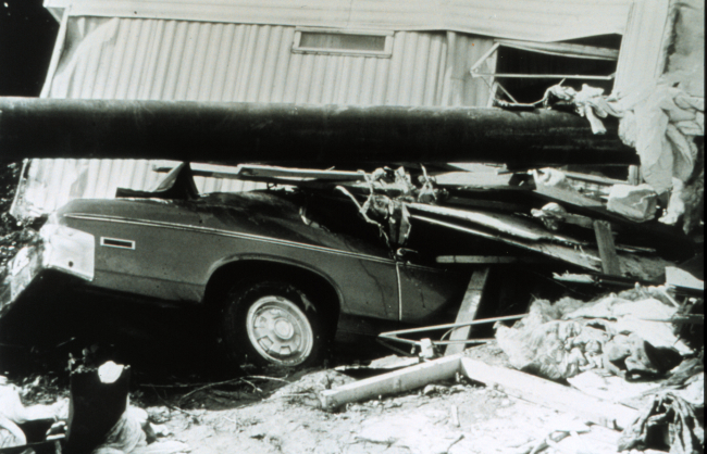 Trailer, vehicle, and utility pole in jumbled pile following a flash flood