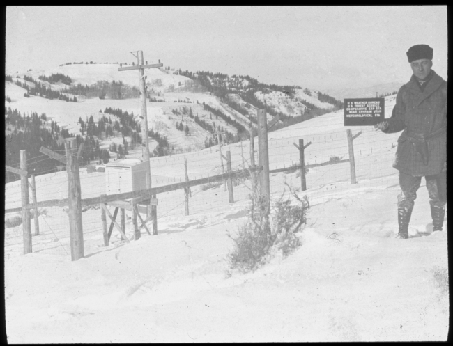 Weather Bureau observer holding sign identifying the meteorological station atthe Weather Bureau/Forest Service site outside of Ephriam, Utah