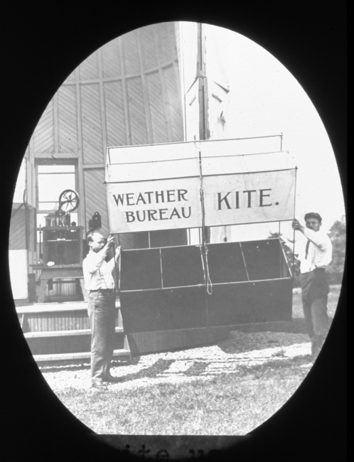 Kite being prepared for launching with kite-reel house in the background