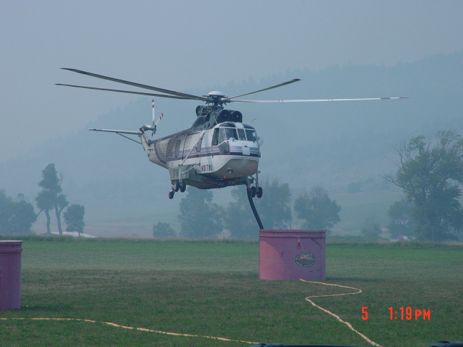 A Sikorsky Helitanker uses a siphon to fill its tank from a phosphateretardant tank while fighting the Derby Fire in Southern Montana