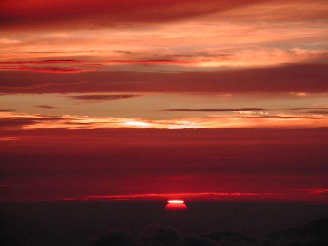 The sun drops between layers of clouds as another day  of measurements endsat the Mauna Loa Observatory