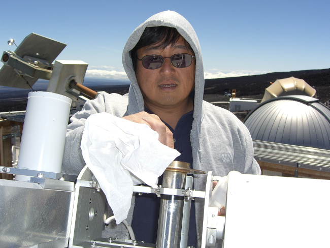 Paul Fukumura-Sawada cleans a sunlight monitoring instrument at NOAA'sMauna Loa Observatory