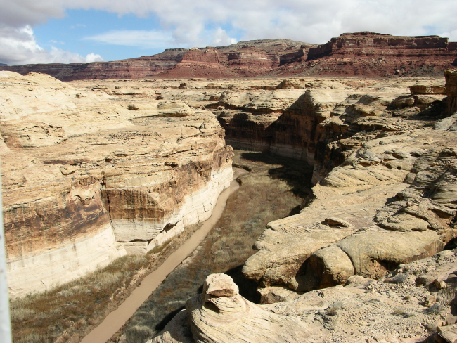 A small stream has cut through the sandstone and overlying red formations of the Colorado Plateau