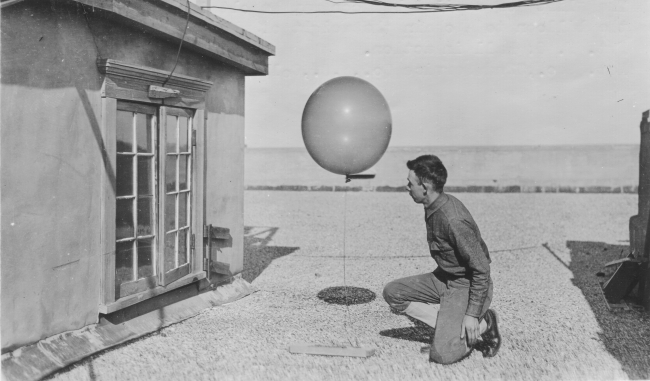 Signal Corps meteorological student Hall checking weather balloon weightprior to launching